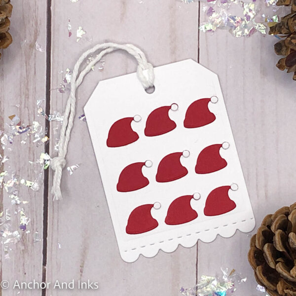 bright red mini santa hats on a holiday tag