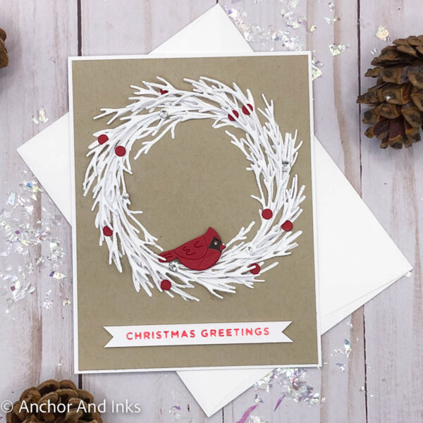 holiday card with a red cardinal sitting on a white pine bough wreath