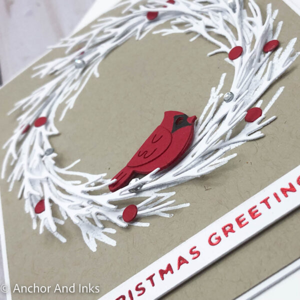 holiday card with a red cardinal sitting on a white pine bough wreath up close