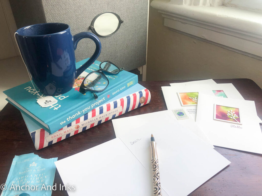 share you story through greeting cards, books about snail mail, glasses and a cup of tea on a desk