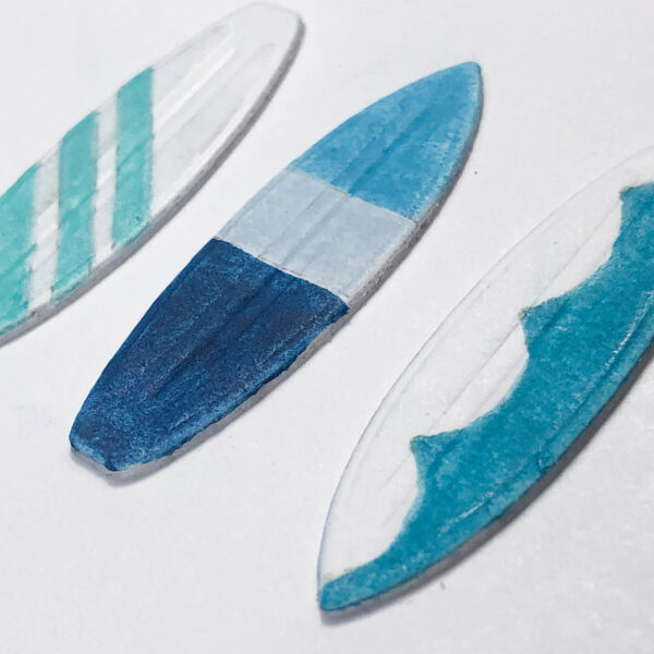 three surfboards in shades of sea glass blues and greens